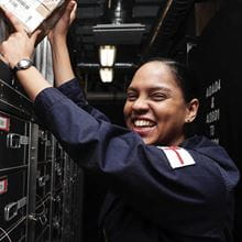 Navy personnel who works under the logistics branch smiling at the camera while working