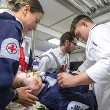 An image showing three Royal Navy healthcare and medical personnel attending to a patient