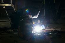 Royal Marine Engineer kneeling on floor and welding.