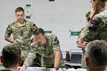 Marines working as a team, leaning over a table planning and discussing their next strategy