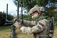 A marine commando setting up a pieve of tech equipment, wearing full camo