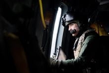 A Royal Marines Aircrewman looking out a window in an aircraft.