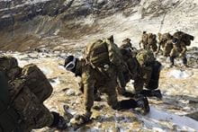 Eight Royal Marines shown climbing a mountain.