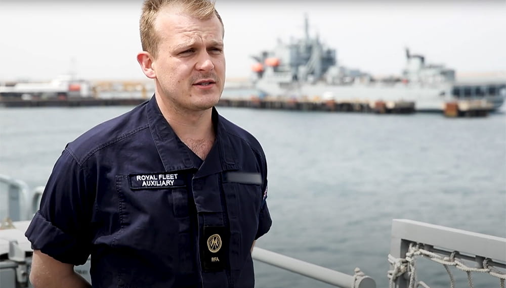 royal-navy-careers-RFA-apprenticeships-03 Navy personnel standing being interviewed with view of ship in the background.