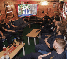 Group of service gathered around and watching a television