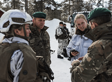 Service people gathered in a circle talking with snow in the background