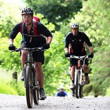 A group of people on mountain bikes ride through a forest