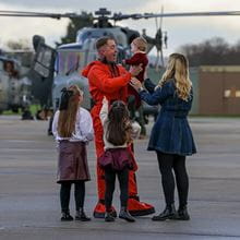 Navy personnel hugging their family, meeting them off of Carrier Strike Group