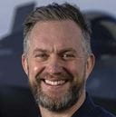 Captain Will Blackett in front of an F-35 on the flight deck of HMS Prince of Wales