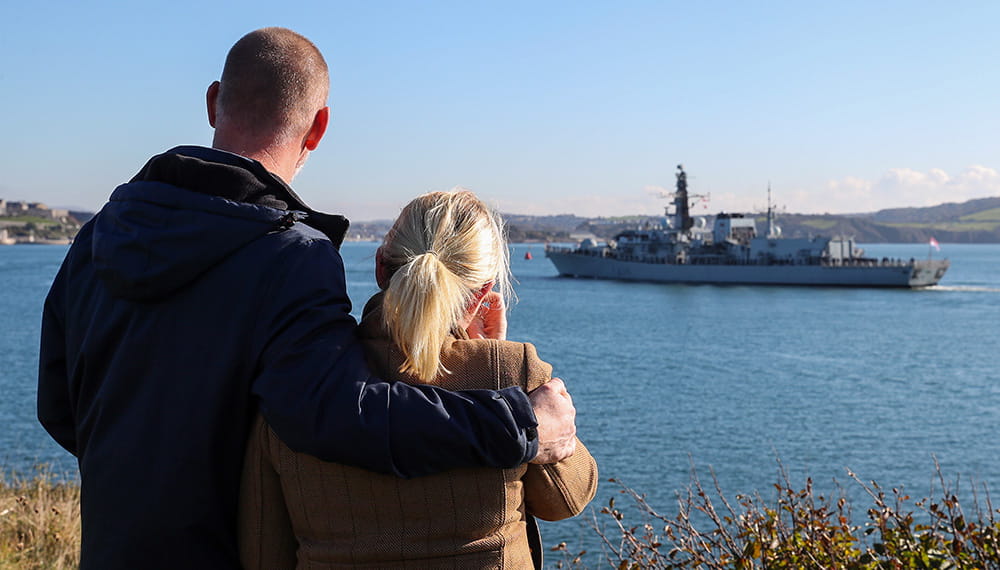 Royal-Navy-Families-09-Deployment-Cycle Man and woman with back to camera watching HMS Montrose sail away