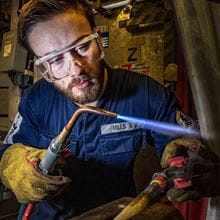 A Royal Navy engineer at work handles a blow torch
