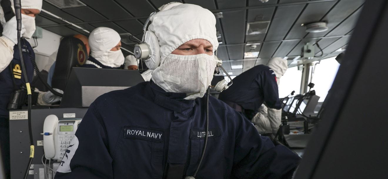 A sailor from HMS Defender's Bridge Team wears anti flash gloves and hood whilst checking navigation during Freedom Of Navigation Operations in the Black Sea.