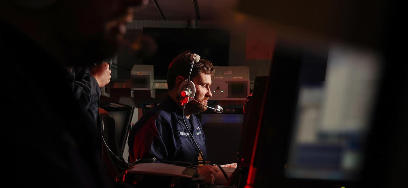 Two Principal Warfare Officers in HMS Defenders Operations Room discuss tactics during an Air Defence Exercise.
