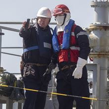 RFA sailors in hard hats and life vests conduct replenishment at sea