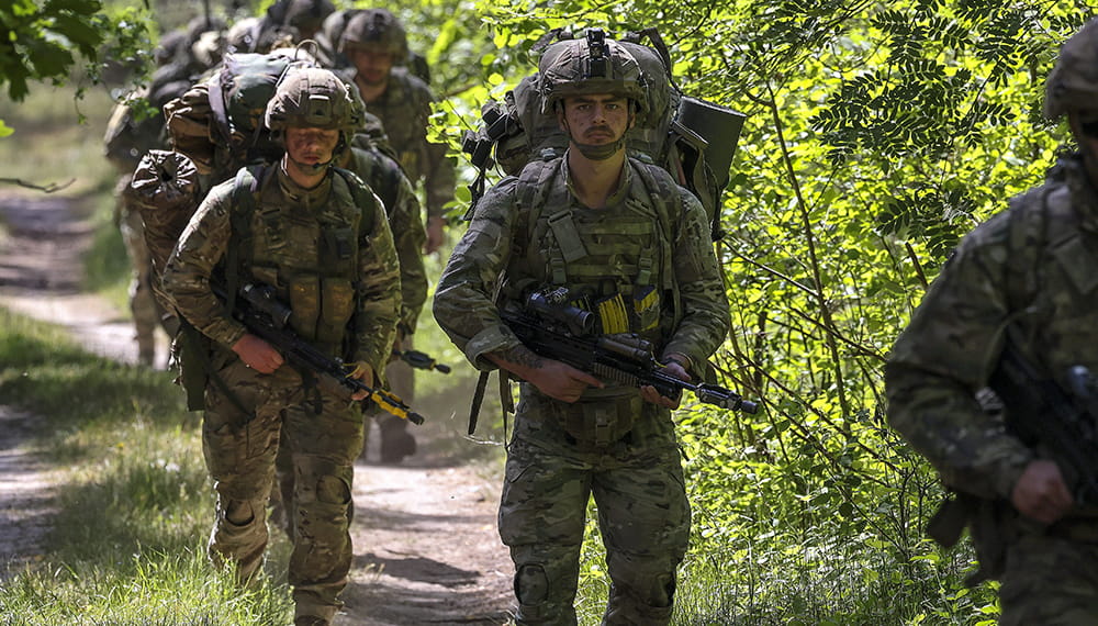 Royal-Navy-What-we-do-protect-03-stabilising-hotspots.jpg Armed Royal Marines walk down overgrown road