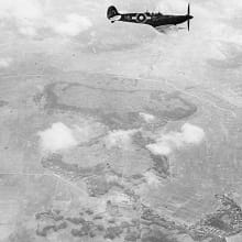 A black-and-white photo shows an aerial view of four simultaneous seafires in Japan, following allied bombardment.