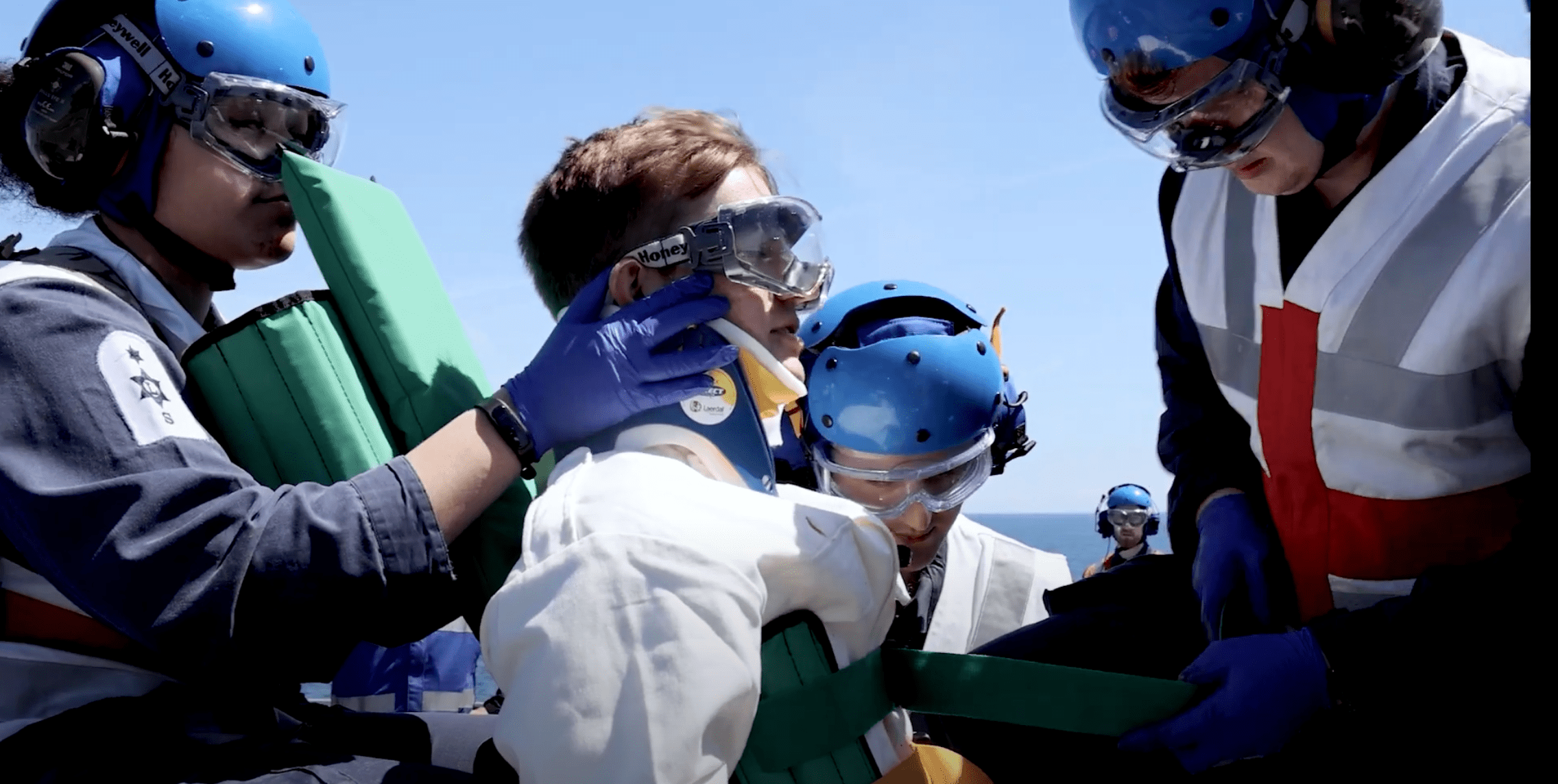 A still taken from a life as a medical officer video where they are attending to a patient outside with three personnel wearing safety gear