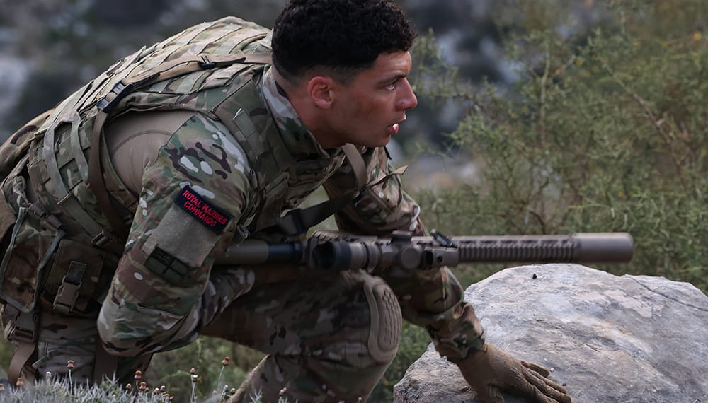 Royal Marines personnel holding weapon and looking straight ahead. 