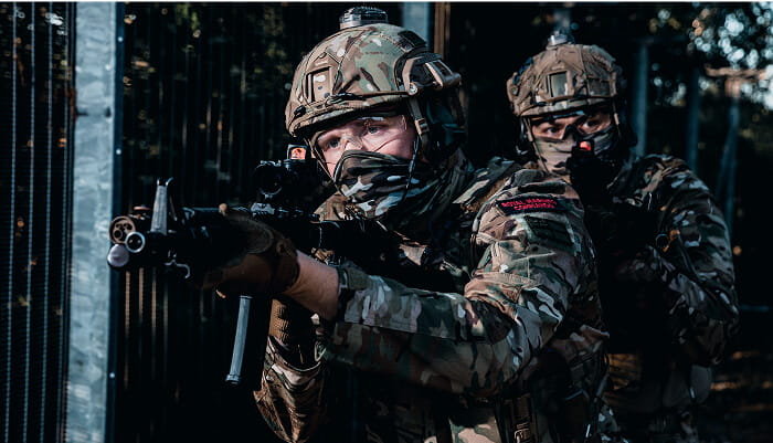 Two Royal Marines with one holding a gun pointing at someone off camera.