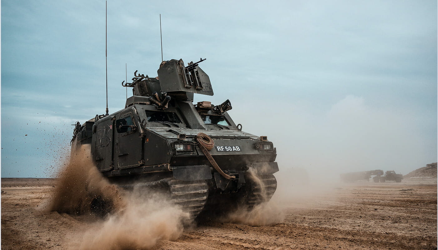 A Royal Marine vehicle travelling across some sand.