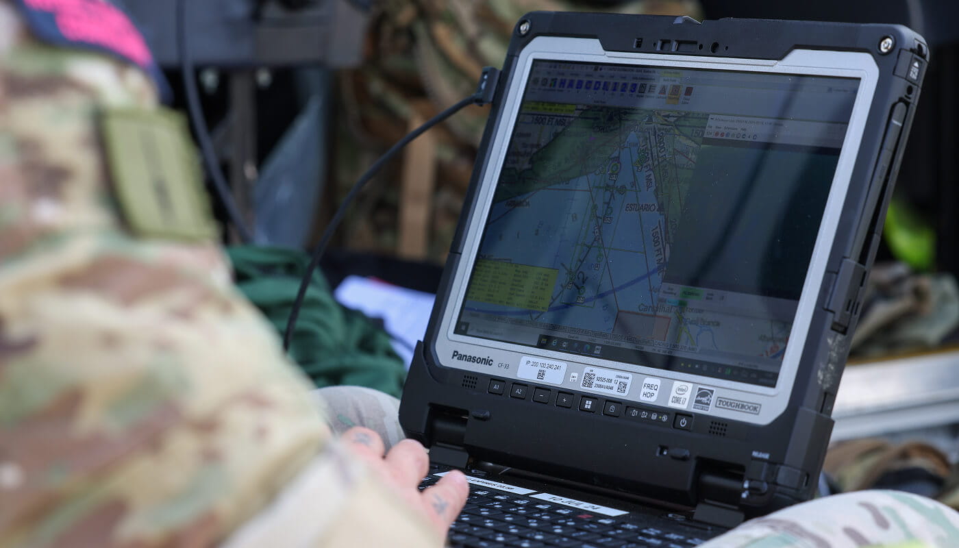 A close up shot of a marine working on a computer device equipment. 