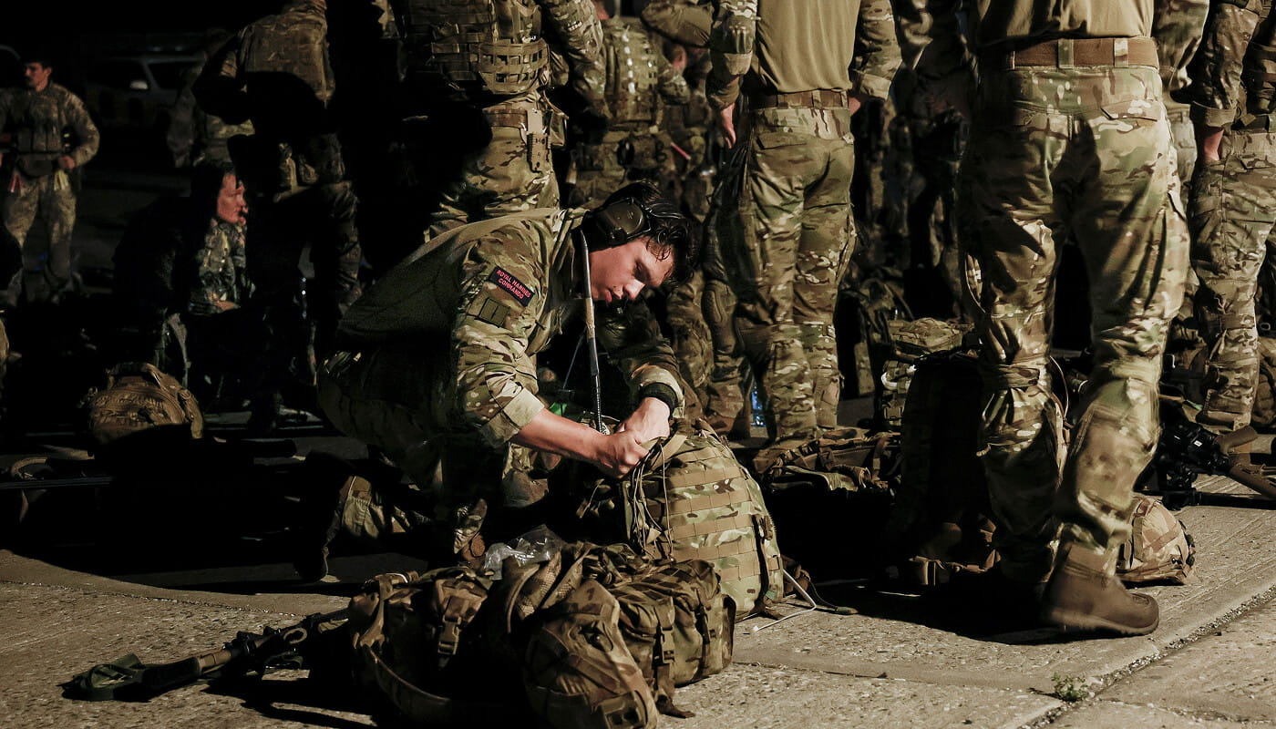 A Royal Marine looking in a bag on the floor.