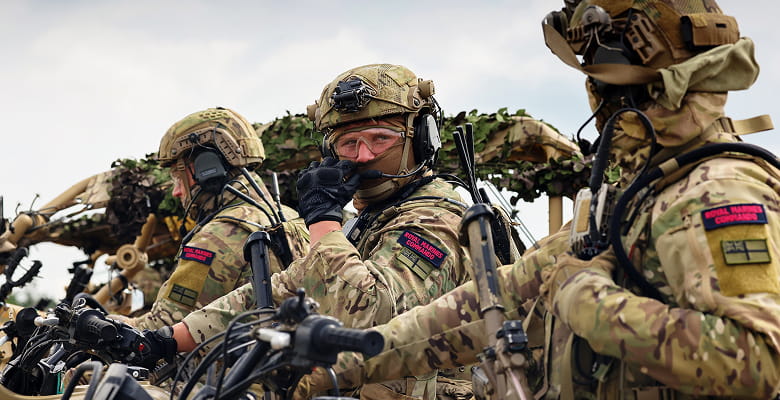 Three Royal Marines all camouflaged and holding guns
