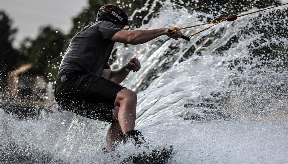 An individual in a black swim suit wake boarding on the sea