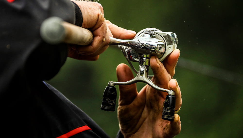 An individual holding a fishing rod adjusts the line