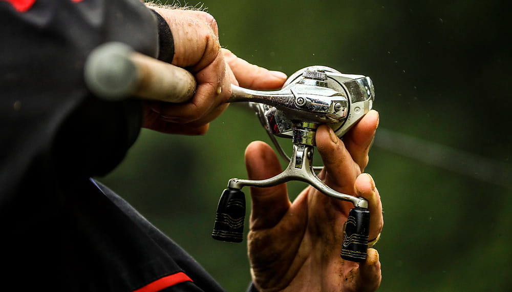 An individual with a fishing rod in their hands adjusts the line