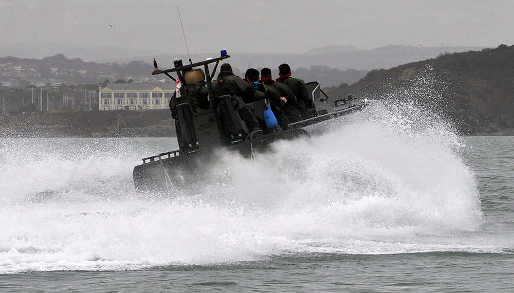 A group of navy sailors aboard a rib boat heading into port