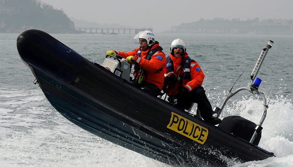 A police rib boat speeding through the sea with the front end of it high above water