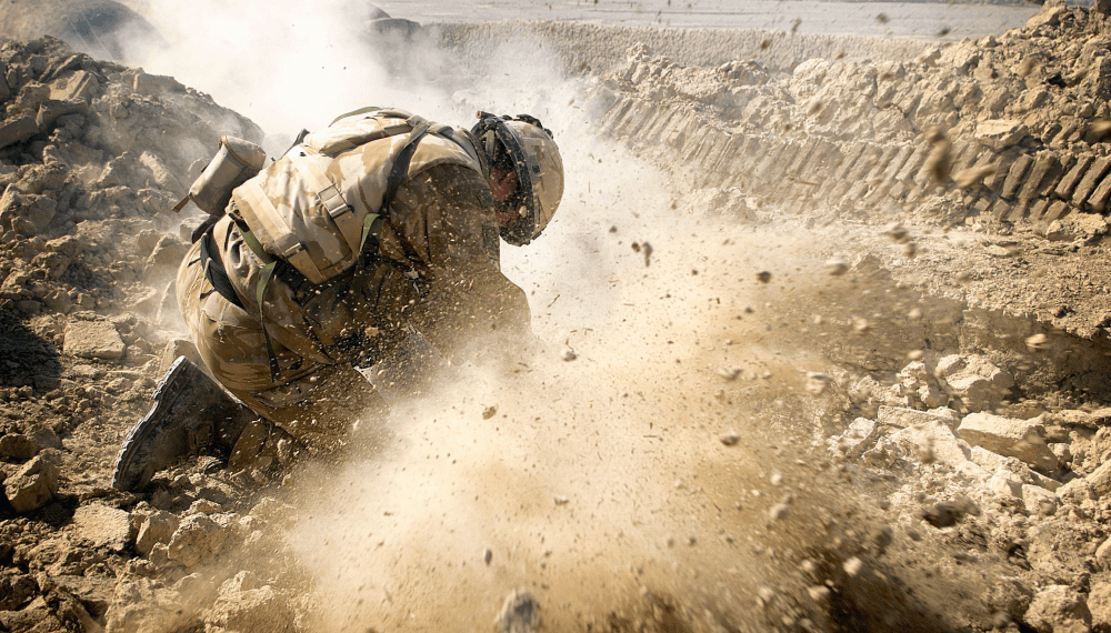A Royal Marine in combat with shrapnel flying towards the camera