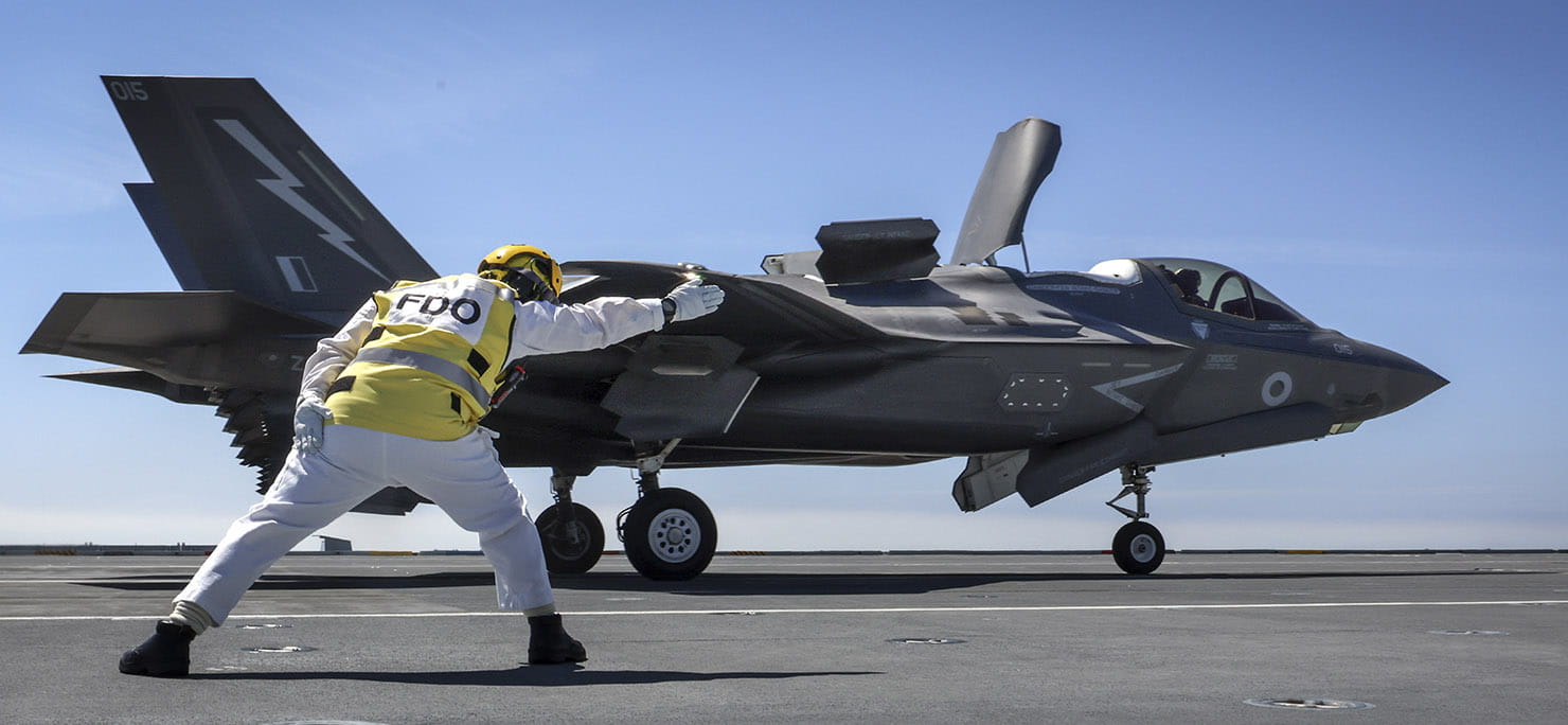 The Flight Deck Officer onboard HMS Prince Of Wales launches the ships first ever F35 flown by Pilot Ben of the Royal Navy.