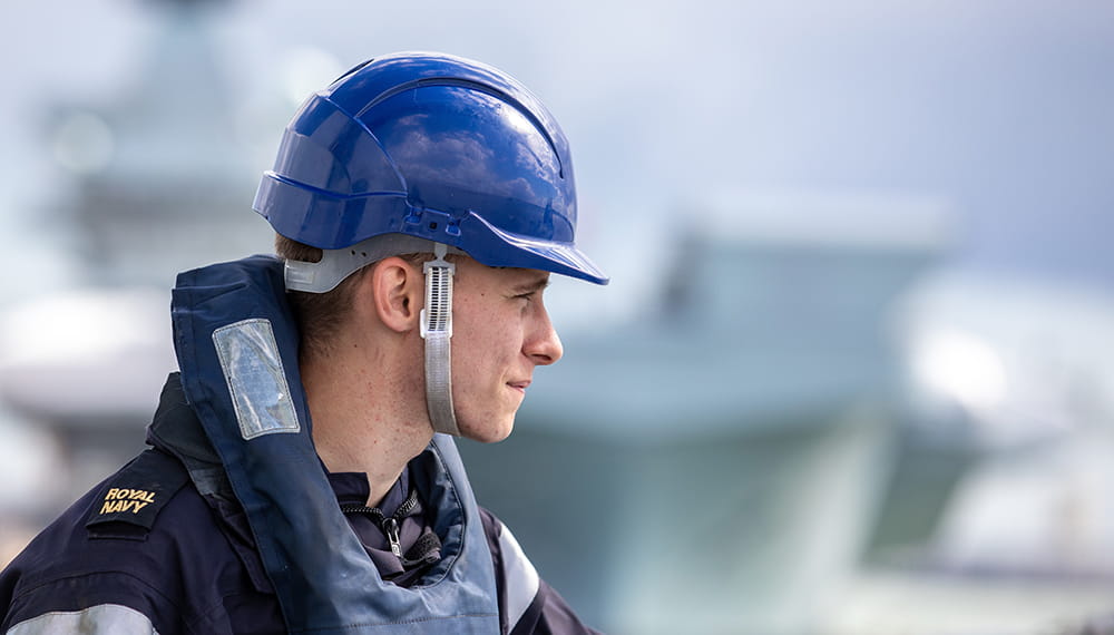 An AB Seaman from the forecastle part of ship looking out to sea as the ship passes one of the aircraft carriers HMS Prince of Wales