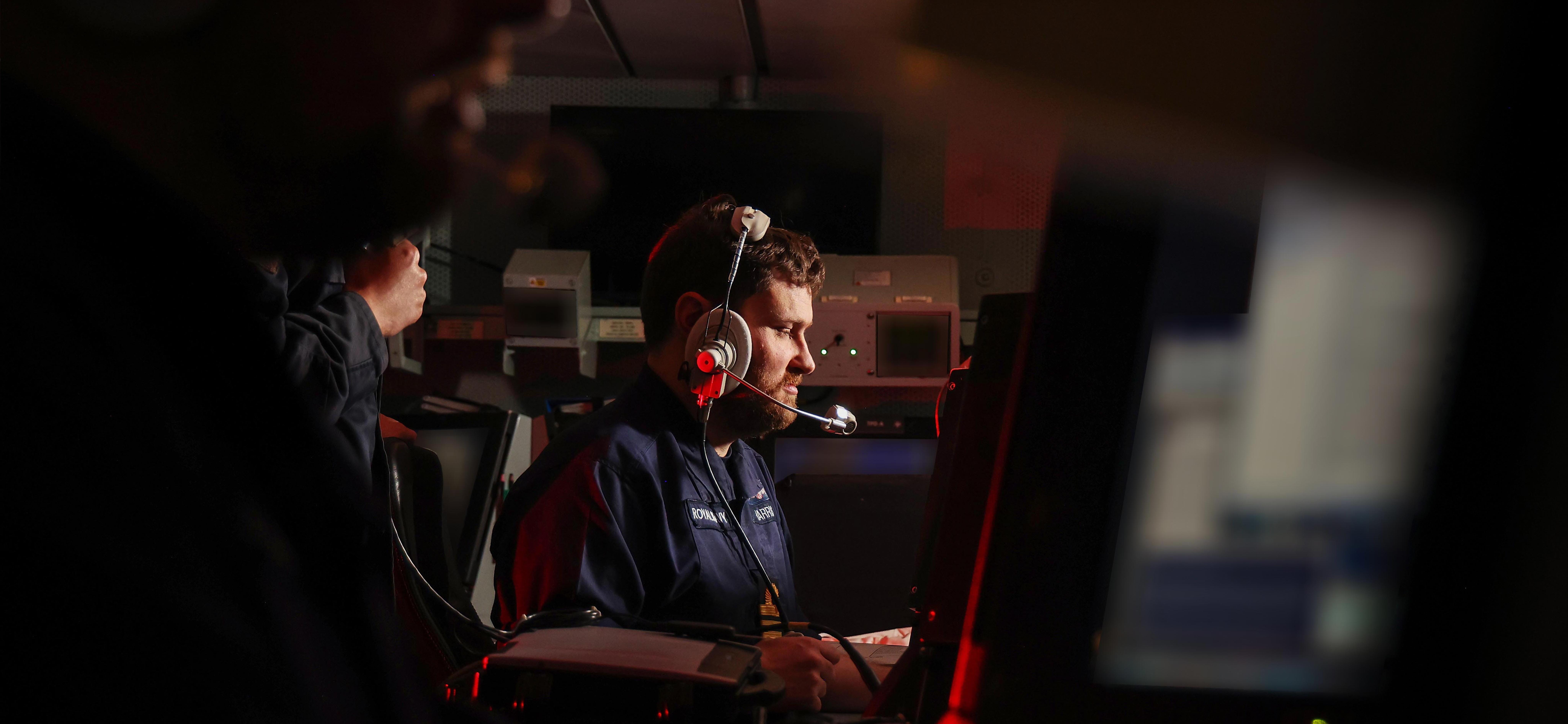 Two Principal Warfare Officers in HMS Defenders Operations Room discuss tactics during an Air Defence Exercise.