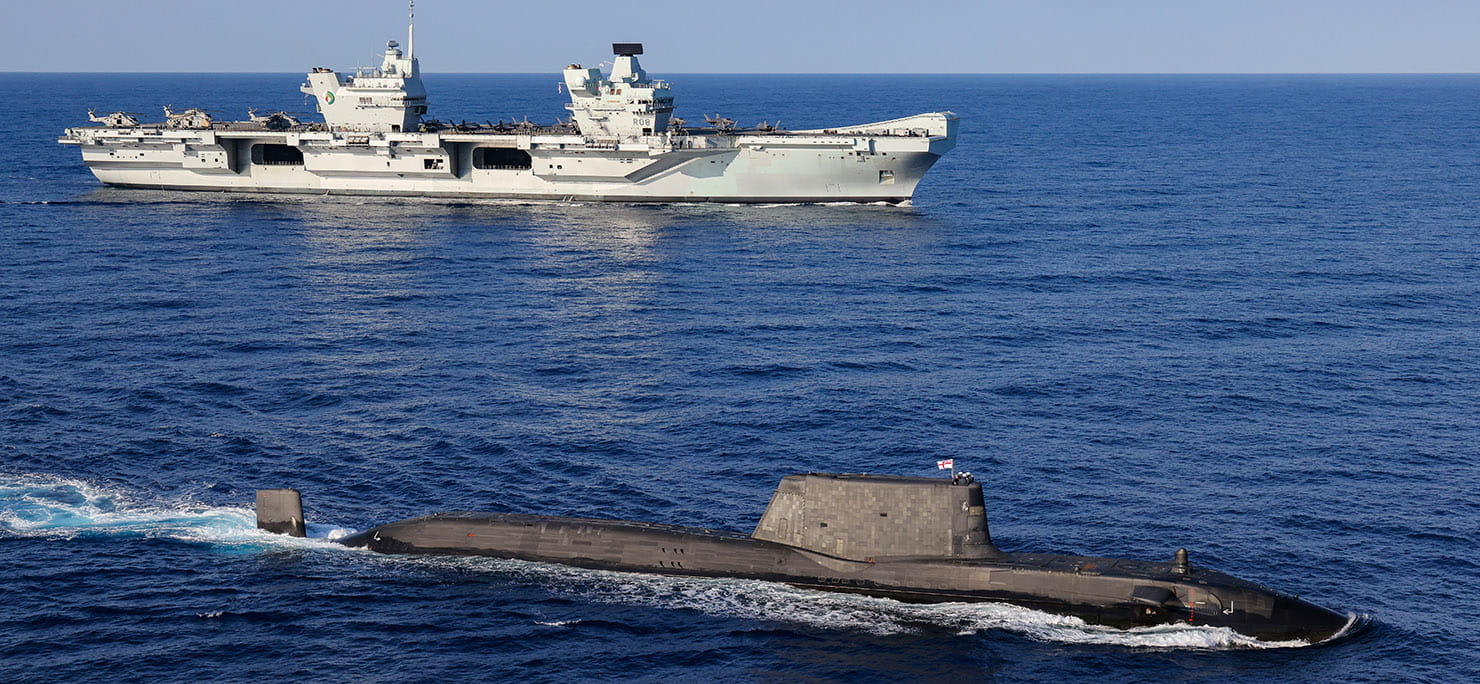 An Astute Class Submarine on the surface with HMS Queen Elizabeth in the background